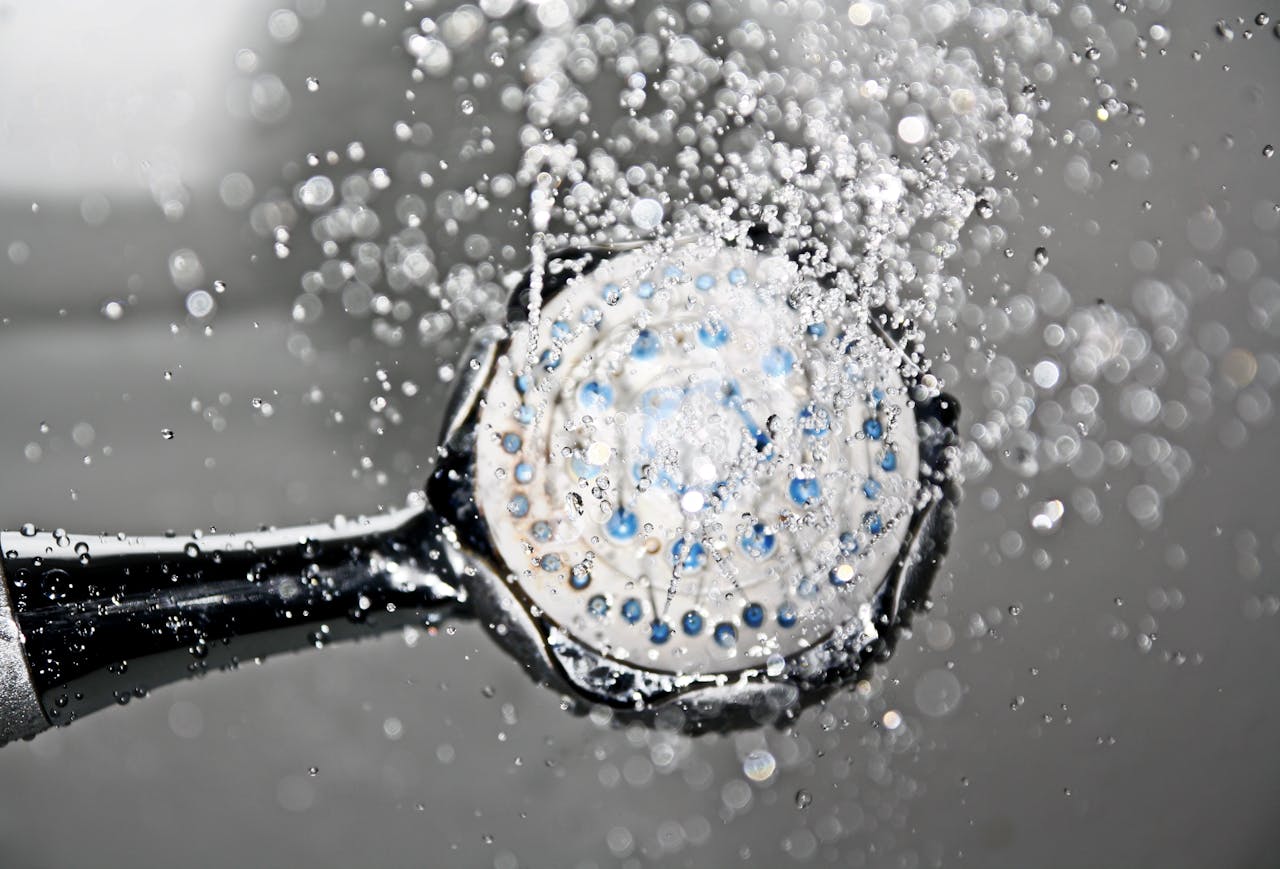 services-02 Close-up of a shower head releasing water droplets, creating a crisp and refreshing bathroom scene.