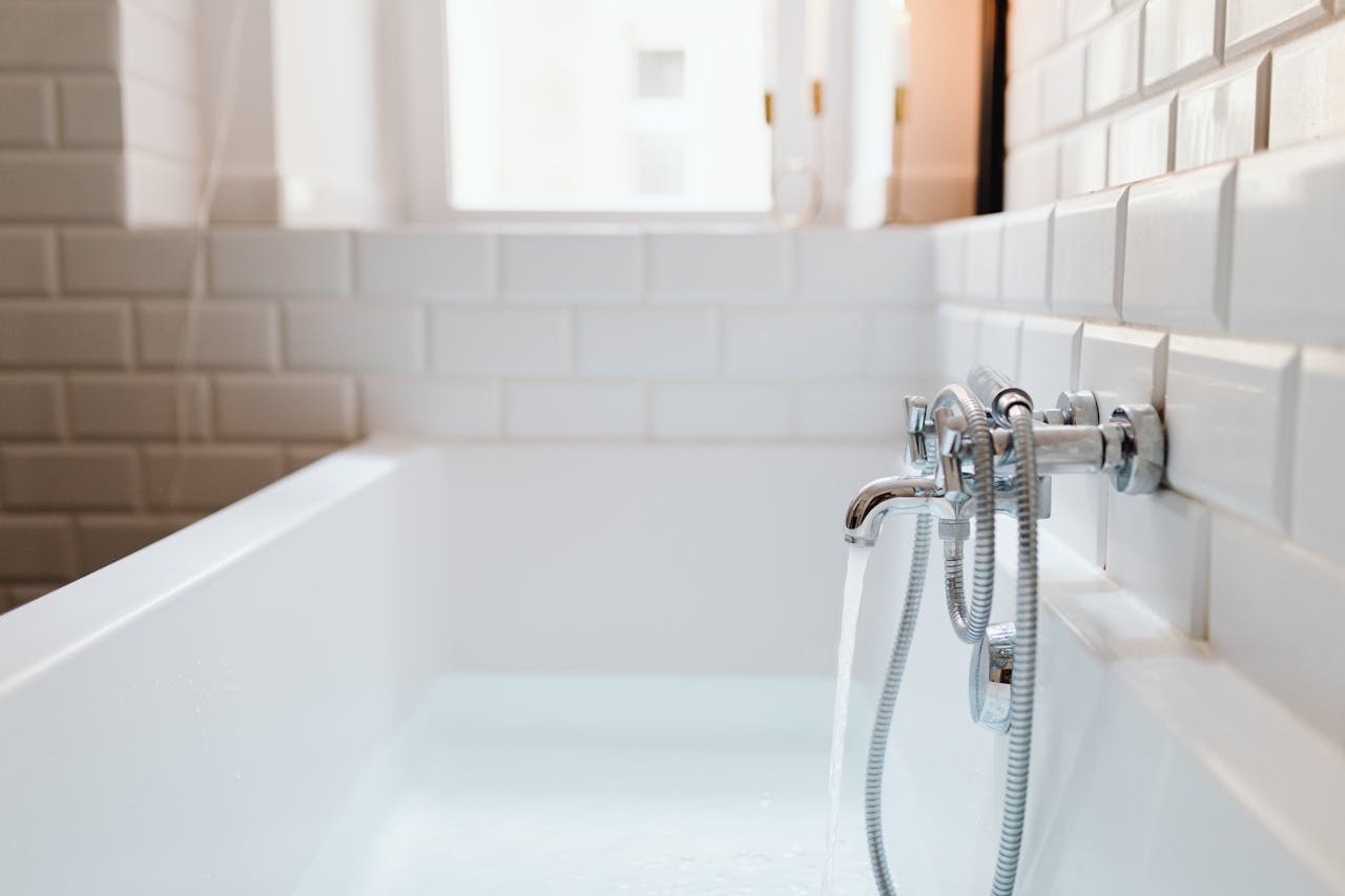 services-04 Stylish ceramic bathtub with modern stainless steel faucet in a sunlit bathroom.
